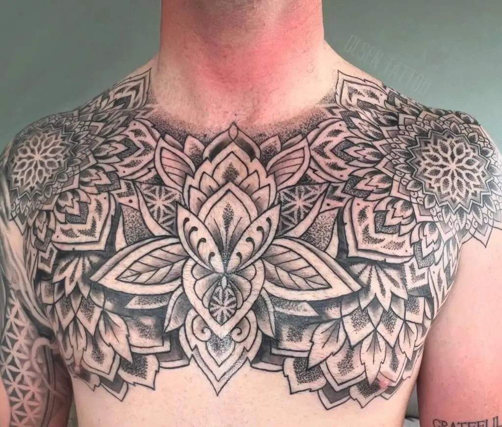 A symmetrical shoulder tattoo with a central mandala and intricate floral designs, mirrored from shoulder to shoulder.