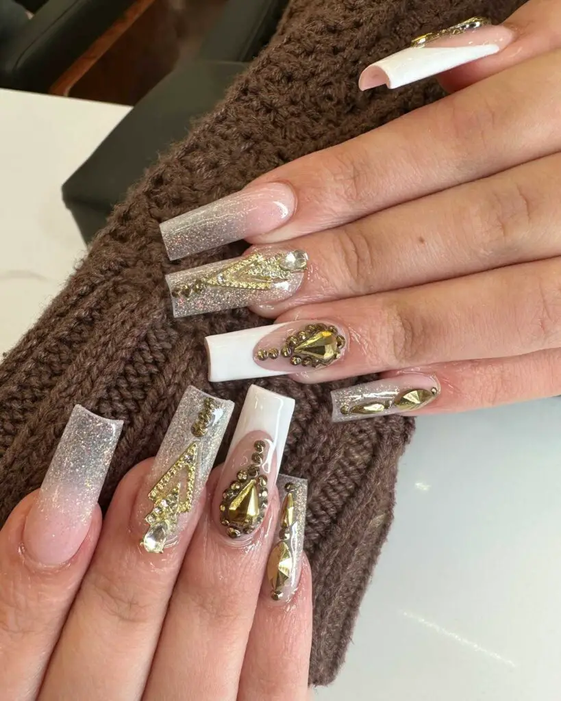 A hand showing off a bold nail design with silver glitter and geometric gold accents on a nude base, for a luxurious and modern look.