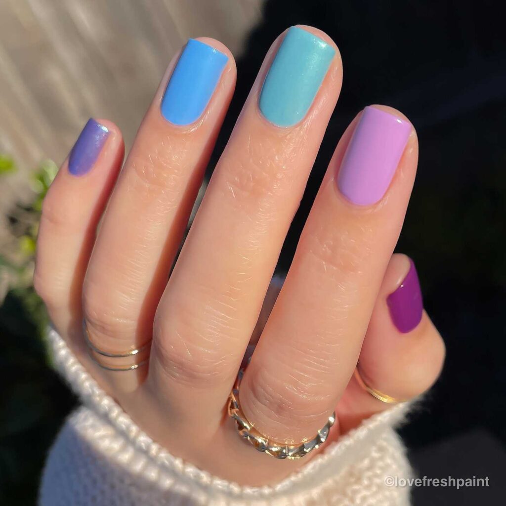 A hand with nails painted in a variety of pastel shades, creating a peaceful and playful pastel harmony.