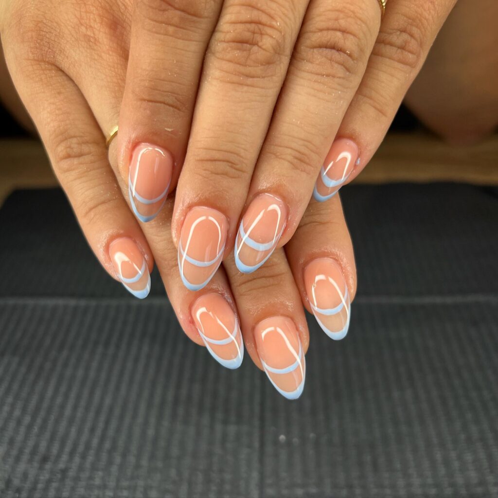 A hand with a modern take on the French manicure, presenting nails with a natural base and blue French tips, offering a fresh and trendy look.