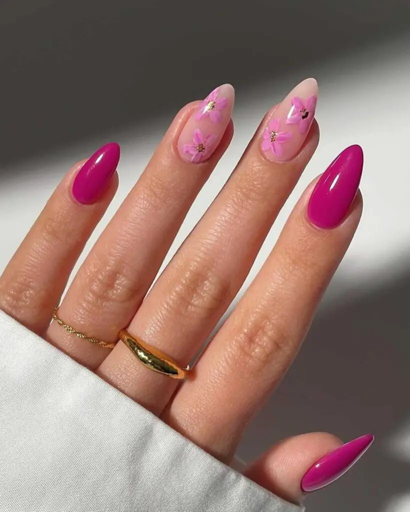 A hand with bold magenta and translucent pink nails, decorated with delicate flower decals for a vibrant and feminine floral look.