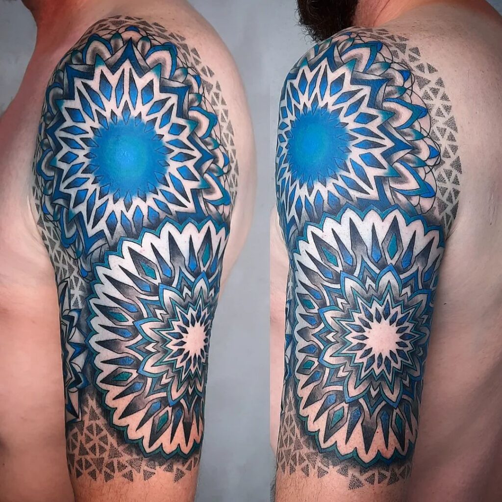 A full sleeve tattoo with a layered blue and black mandala design, giving a three-dimensional effect on the skin.