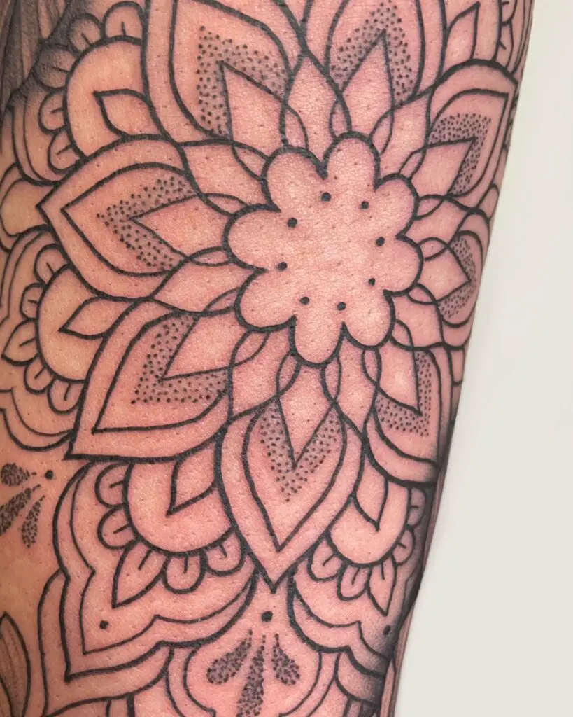 Close-up of a floral mandala tattoo with precise dot work and shading that creates a blooming effect.