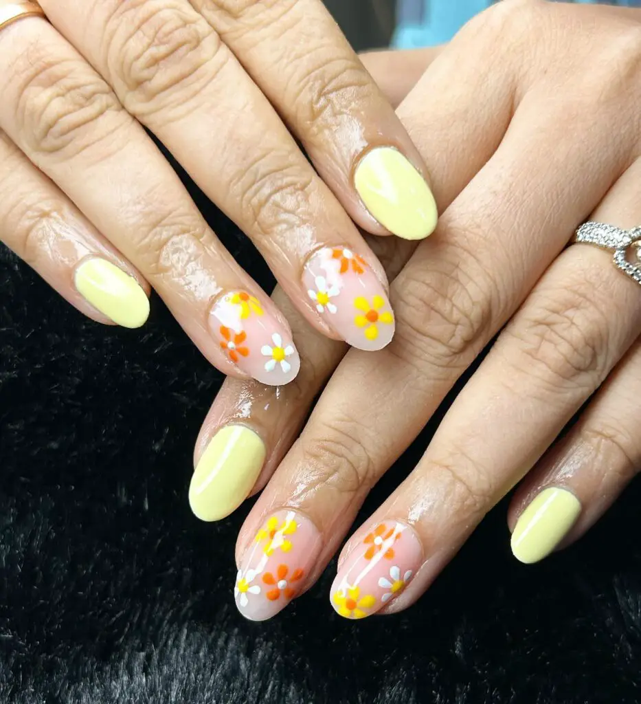 French tip nails with a translucent base, decorated with cheerful yellow and white daisy designs for a fresh, floral look.