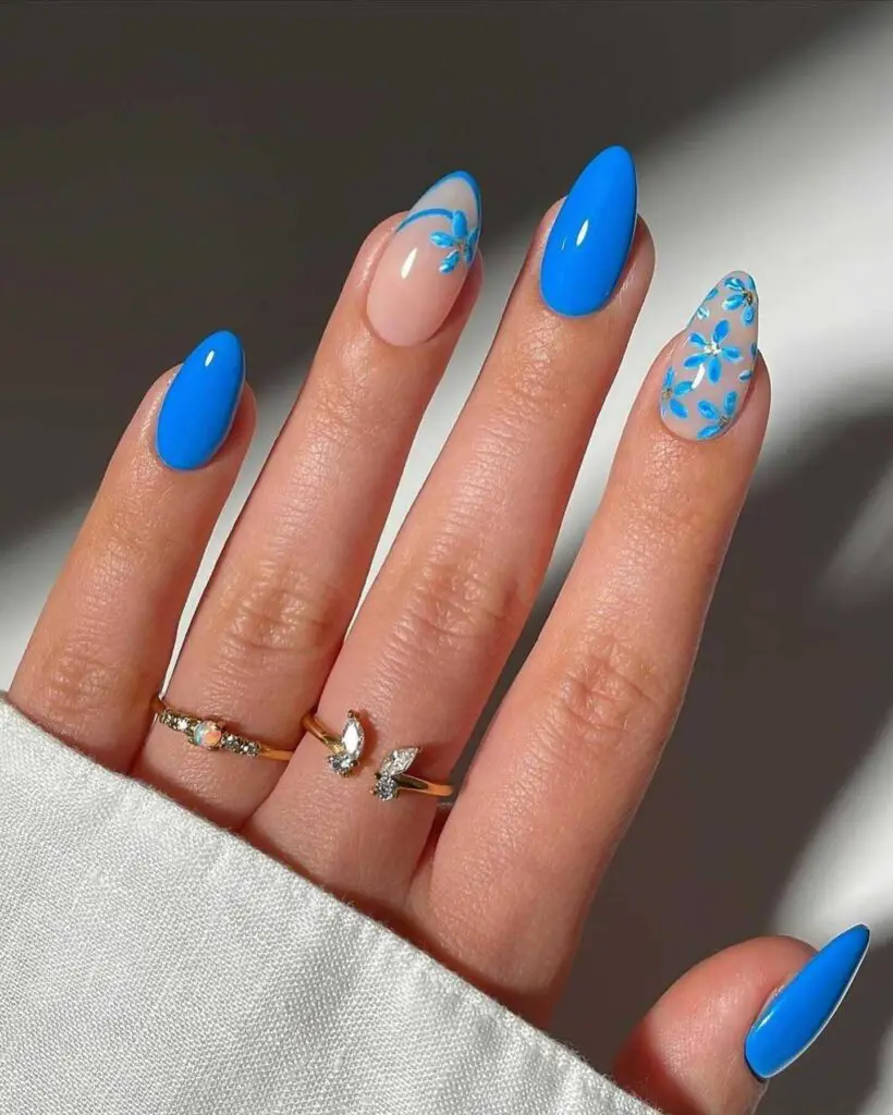 A hand with bright blue nails decorated with light blue floral designs, capturing the cheerful essence of a sunny day.