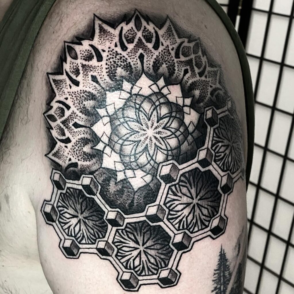 A black ink tattoo on the upper arm with a central mandala surrounded by a honeycomb pattern.