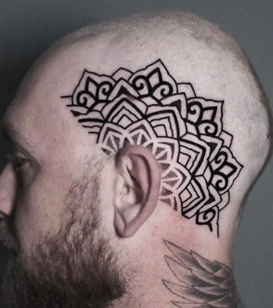 A side head tattoo resembling a crown, with a complex mandala pattern.