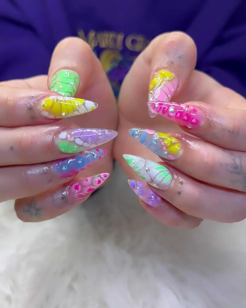 Hand with long, clear nail extensions filled with colorful, candy-like confetti for a fun, festive look.