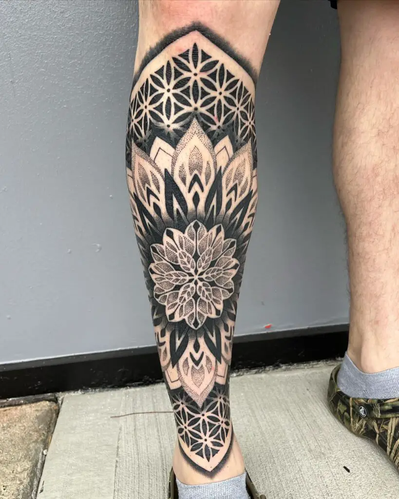 Lower leg covered with a bold mandala tattoo in dark black ink, featuring contrasting geometric patterns.