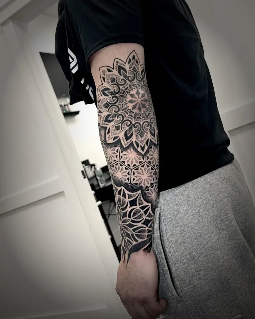 A full sleeve tattoo featuring a seamless blend of floral and geometric mandala patterns with intricate shading.