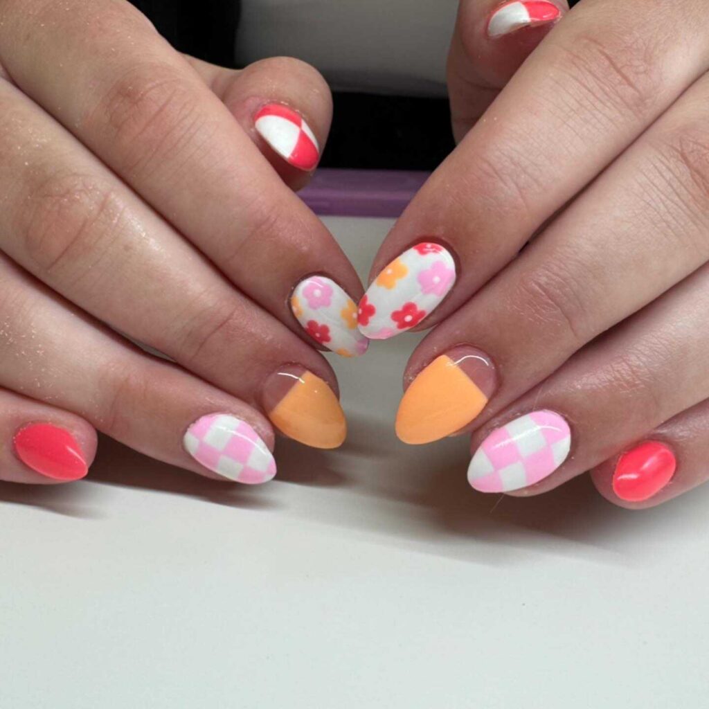 Bright spring-inspired nail art featuring pink and orange tones with checkered and floral patterns.