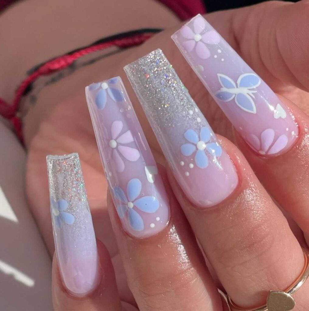 Coffin-shaped nails with pastel blue floral art and glitter detailing, mirroring the charm of a springtime bloom.