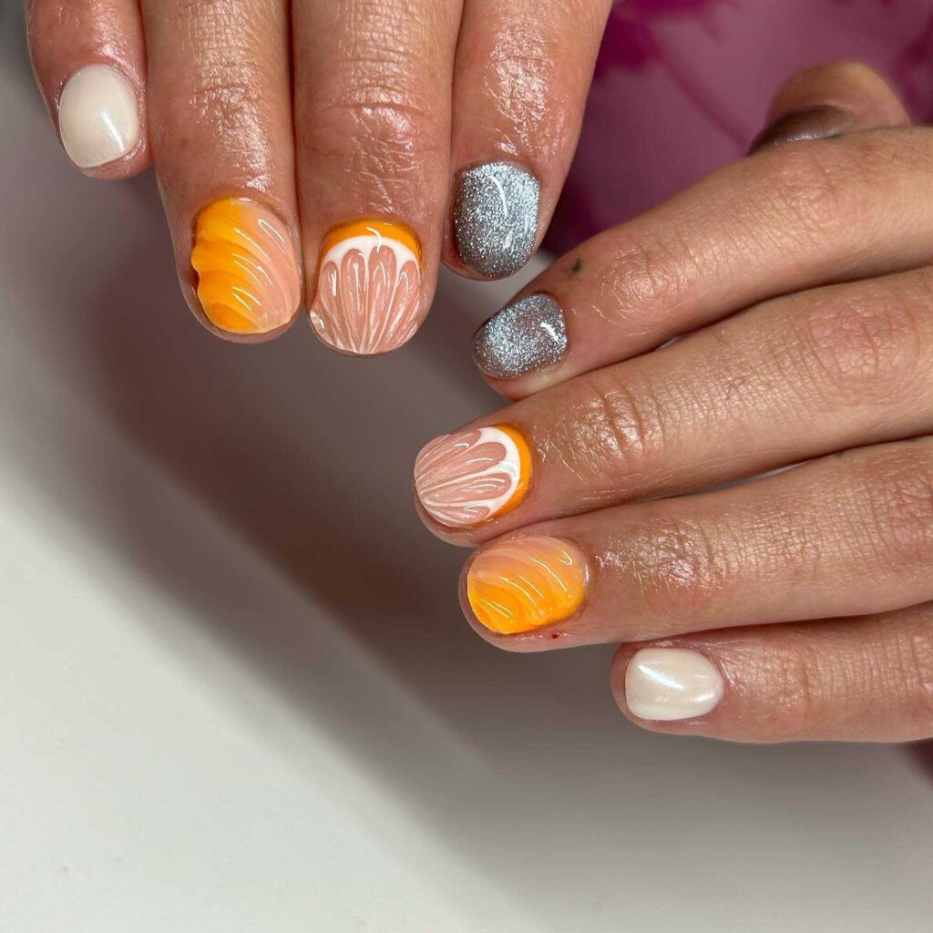 Nails featuring a sunset gradient from white to orange with silver glitter and shell pattern accents, embodying the warmth of a spring dusk.