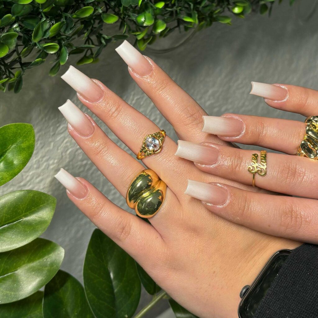 Long, coffin-shaped nails with a sheer finish and delicate white accents, offering a touch of simple elegance.