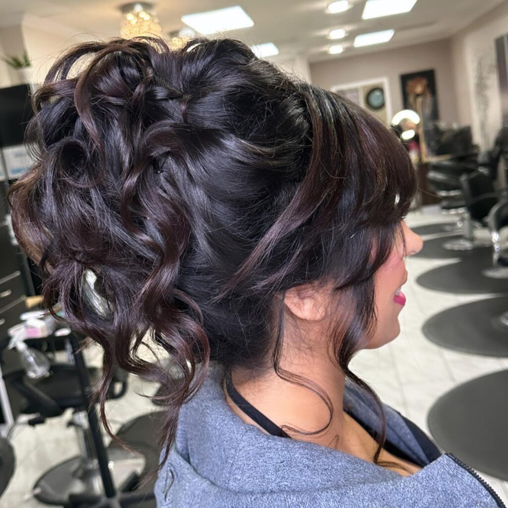 A woman showcasing a chic prom updo with a twist and playful spiraled curls, designed for a sophisticated and stylish look.