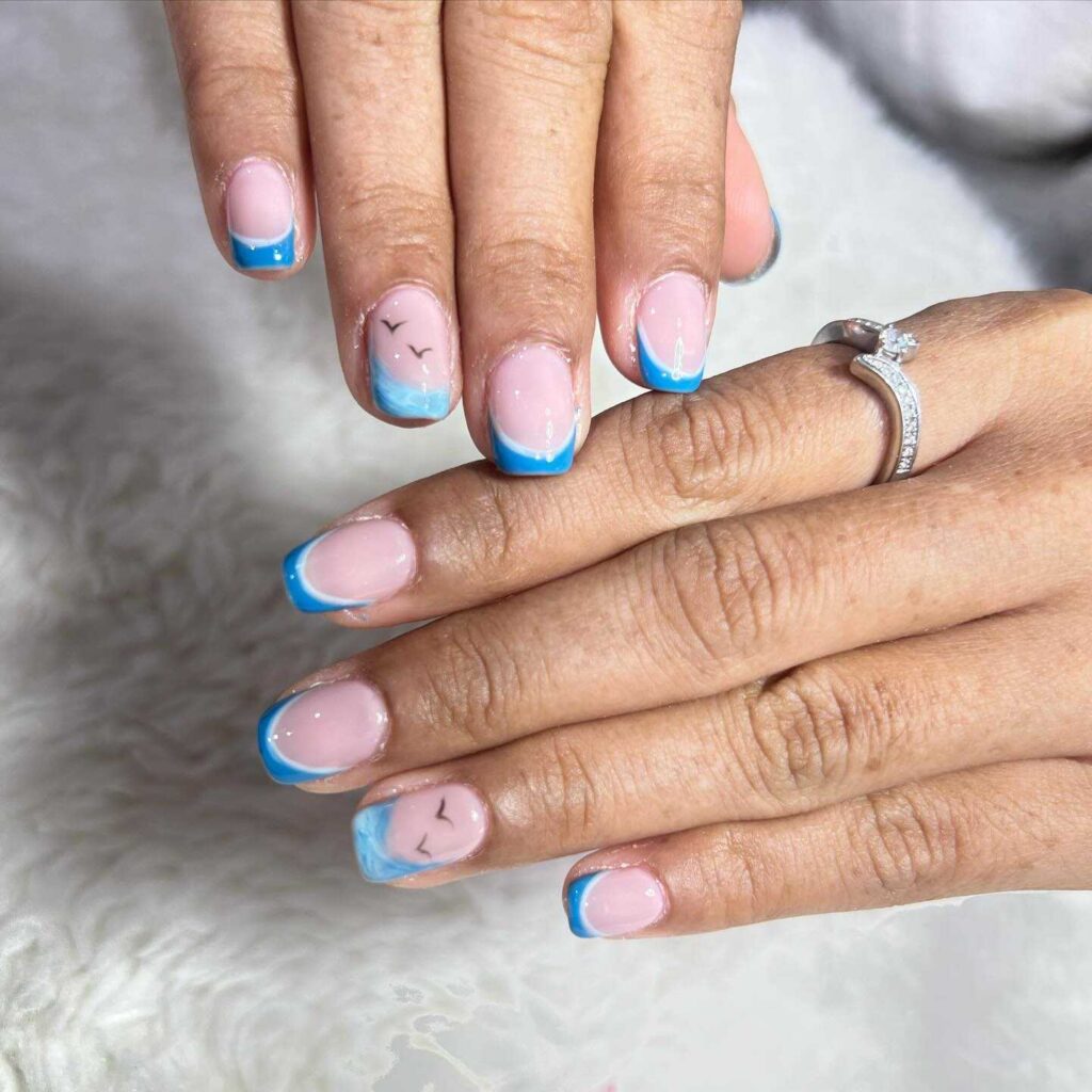 French tip nails with a sky blue edge and soft pink base, adorned with charming bird silhouette accents.