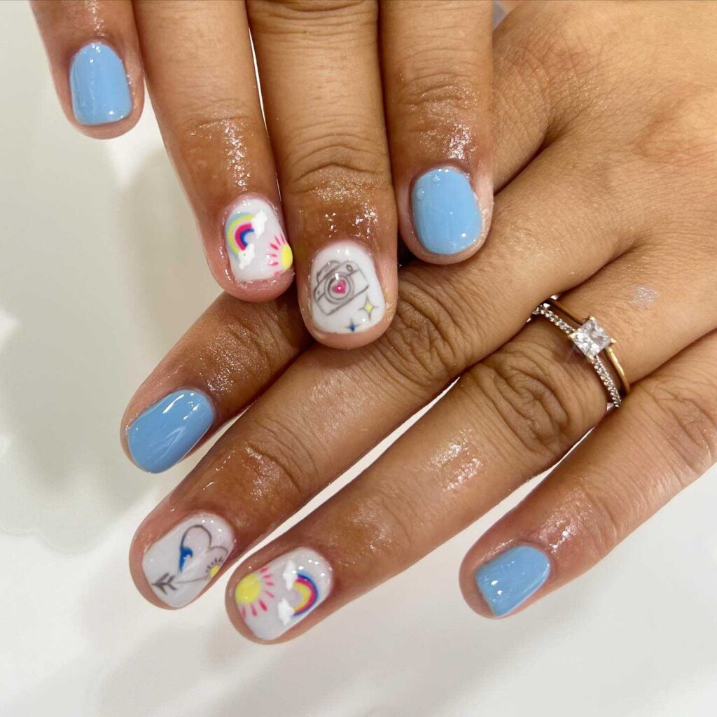 Nails painted with whimsical unicorn and rainbow designs on a pastel base, invoking a magical and playful vibe.