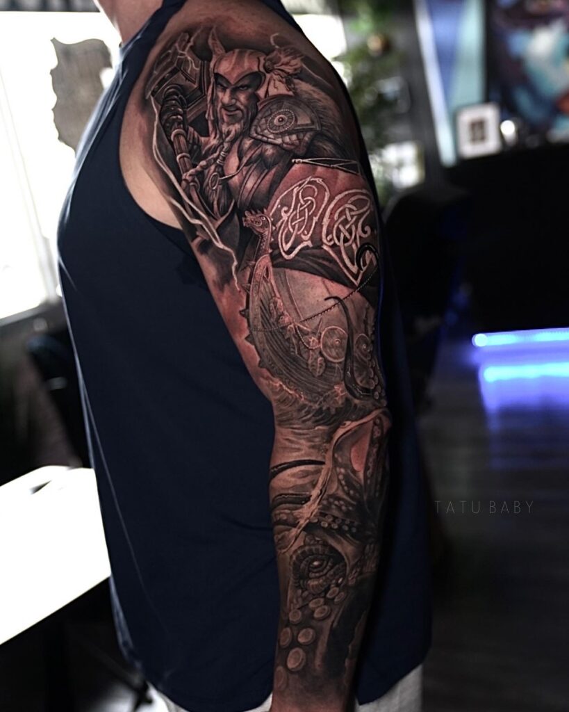 A sleeve tattoo of a Viking warrior in armor with detailed shading and red accents, representing Norse bravery.