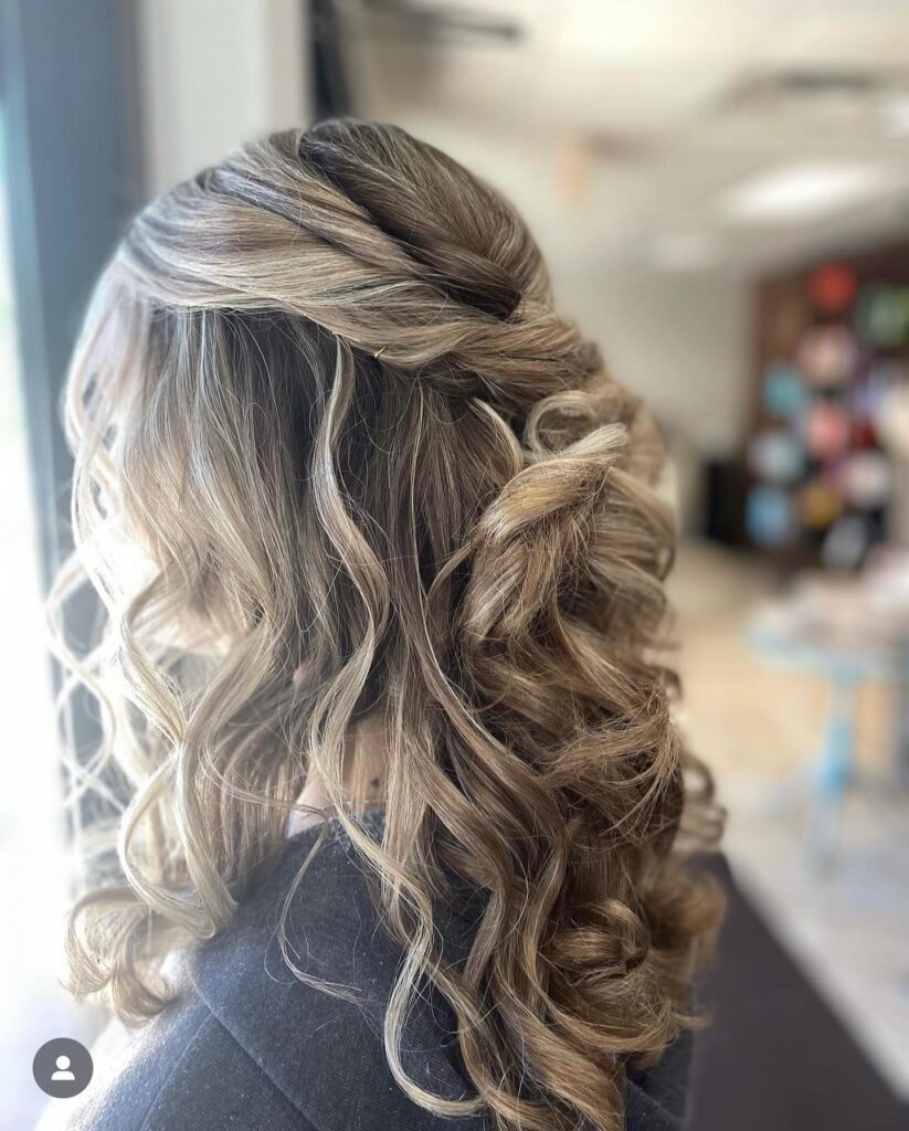 A back view of a half-up hairstyle with blonde twists and cascading curls, styled for a sophisticated prom night elegance.