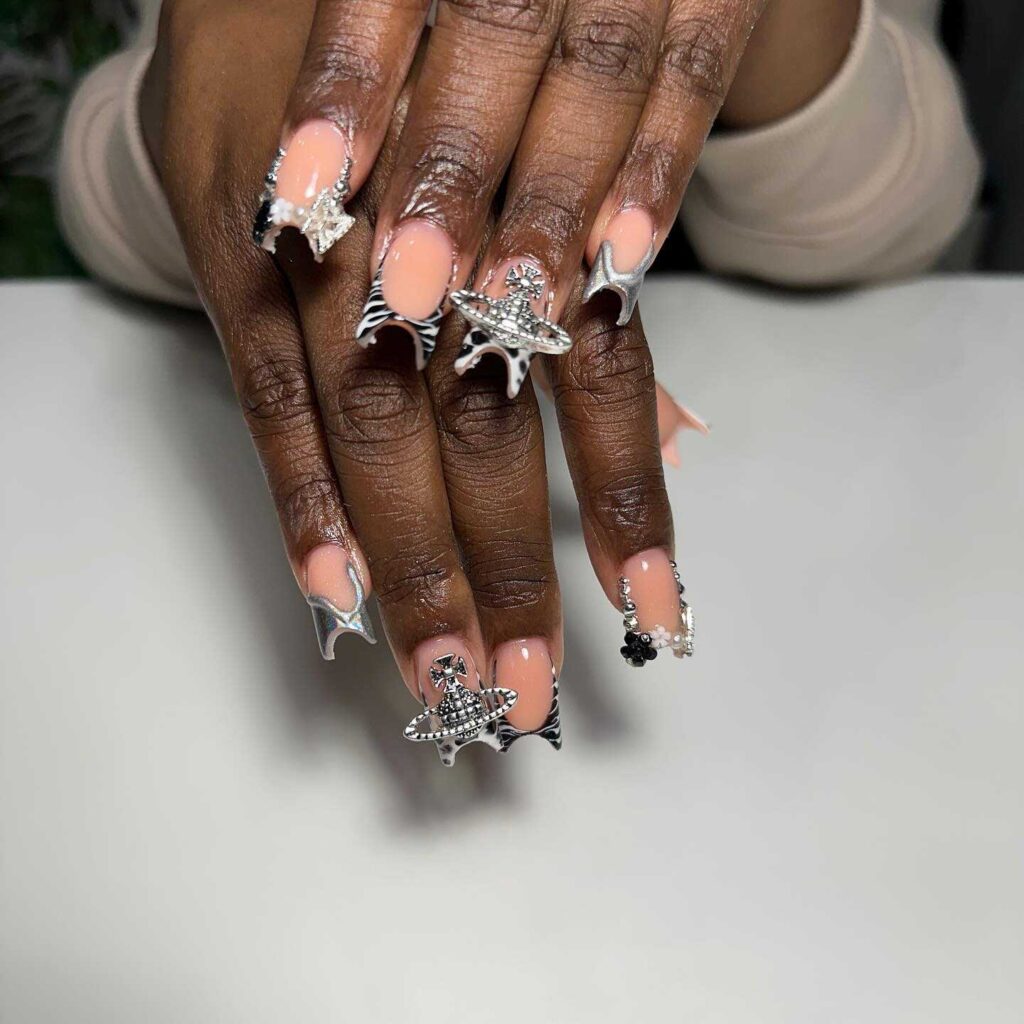 Long nails painted peach with silver starfish and sea-themed jewelry accents, invoking an underwater fantasy theme.