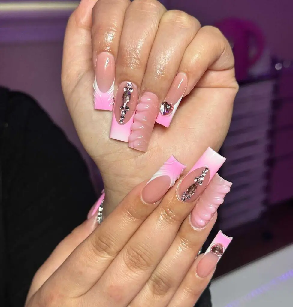 A chic ruffled French manicure with pink accents and adorned with rhinestones and metal studs for a playful look.